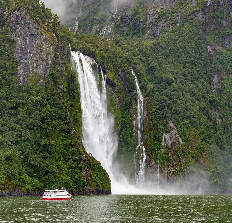 A tour boat near Lady Bowen Falls in Milford Sound during the summer.